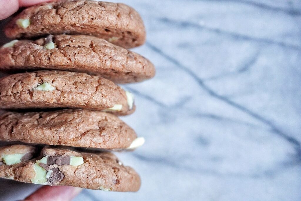 woman holding 5 chocolate mint chip cookies.