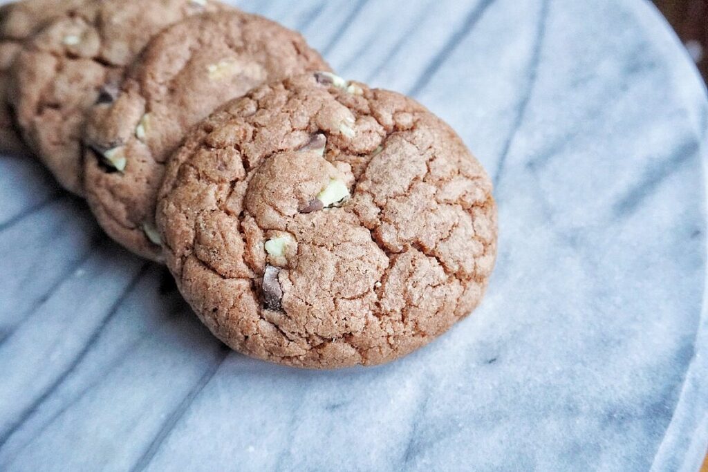 4 double chocolate mint chip cookies lined up on a marble tray.
