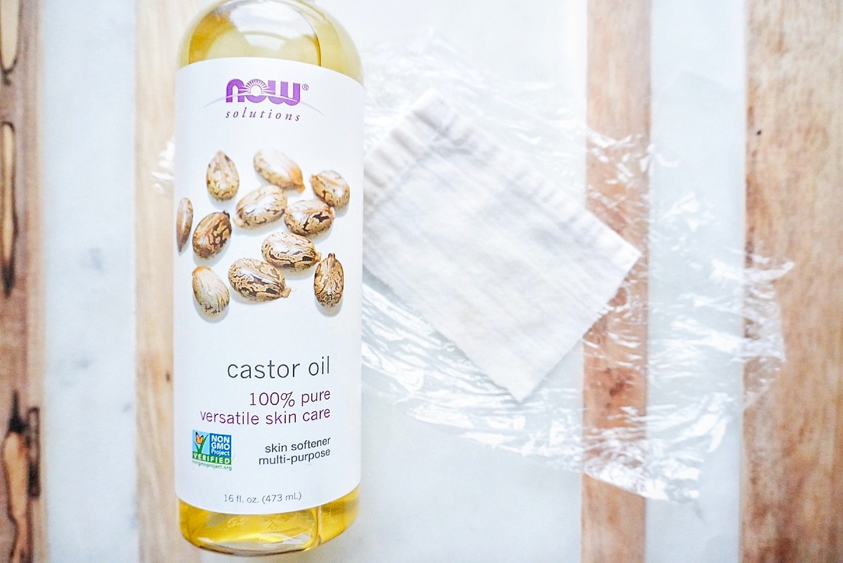 castor oil bottle on a marble counter next to a castor oil pack.