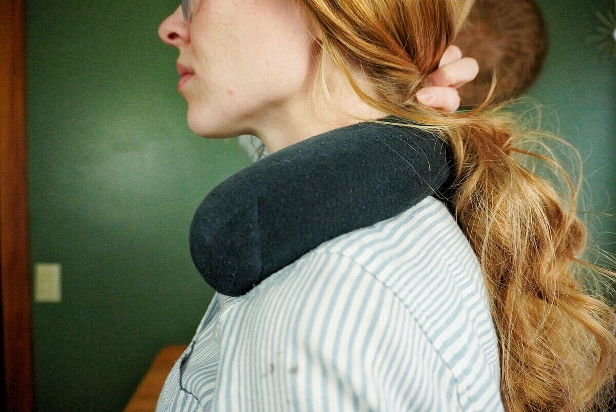 womans holding hair back with rice sock heating pad on shoulders.
