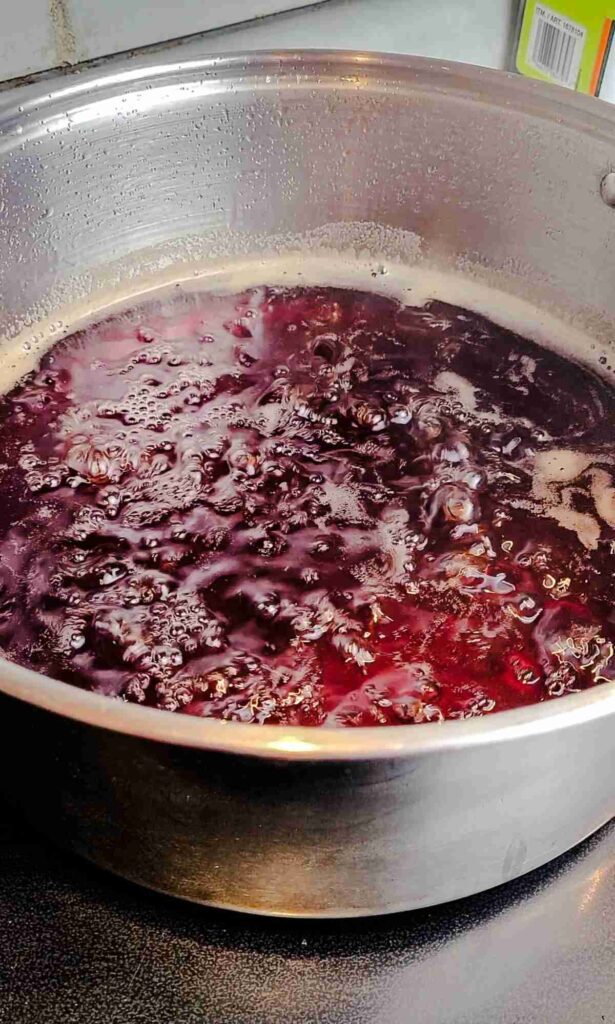 dark red strawberry syrup rolling boiling in pot to reduce and thicken 