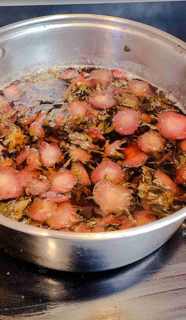 pot with strawberry tops that are faded light pink from being boiled
