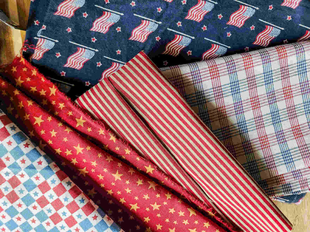 multiple different patriotic fabrics arranged on a counter top. 