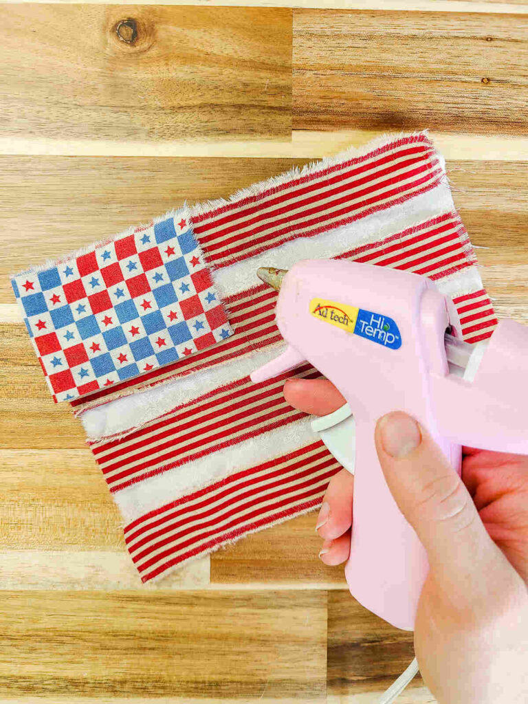 woman gluing bunting flag together with a hot glue gun. 