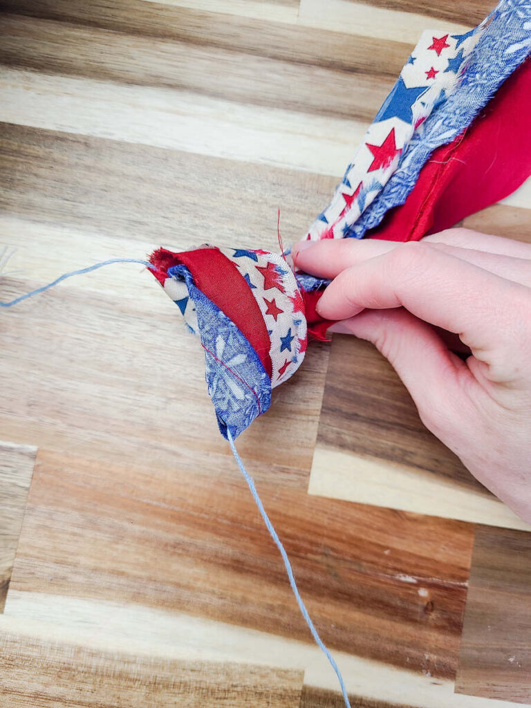 woman tying 3 pieces of fabric strips on to string for banner