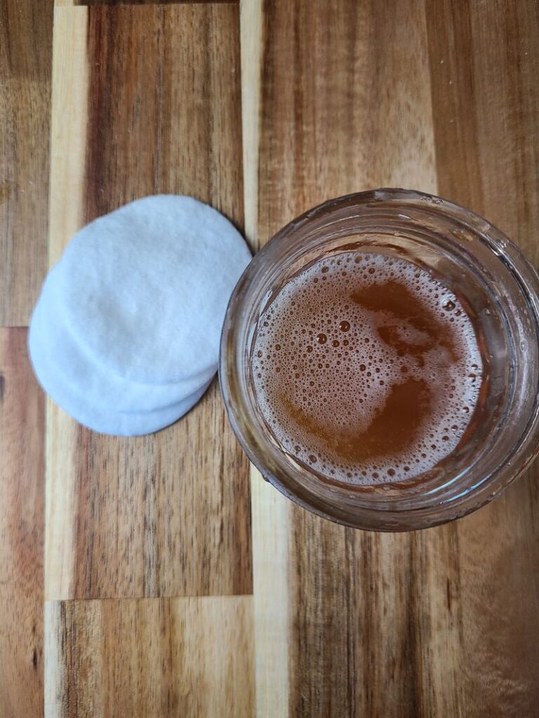 open jar of wild parsnip salt solution next to 3 cotton pads