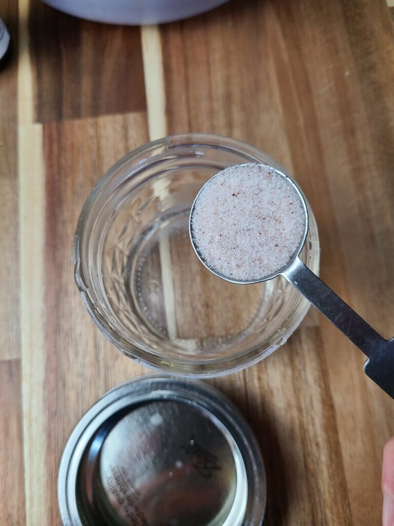 woman pouring salt into jar of water