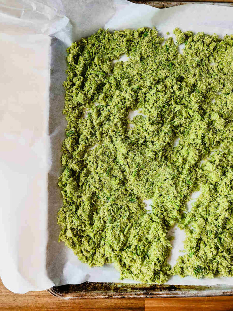 garlic scape salt spread out on parchment paper lined cookie sheet