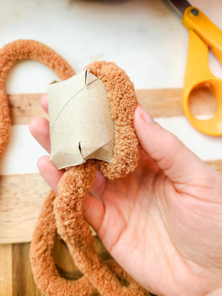 woman wrapping yarn around toilet paper roll 