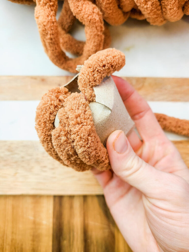 woman wrapping yarn around toilet paper roll 