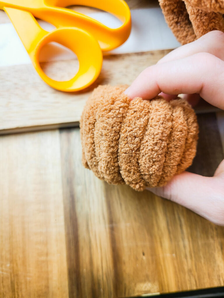 woman carefully pressing edges of plush yarn pumpkin to make it more round 