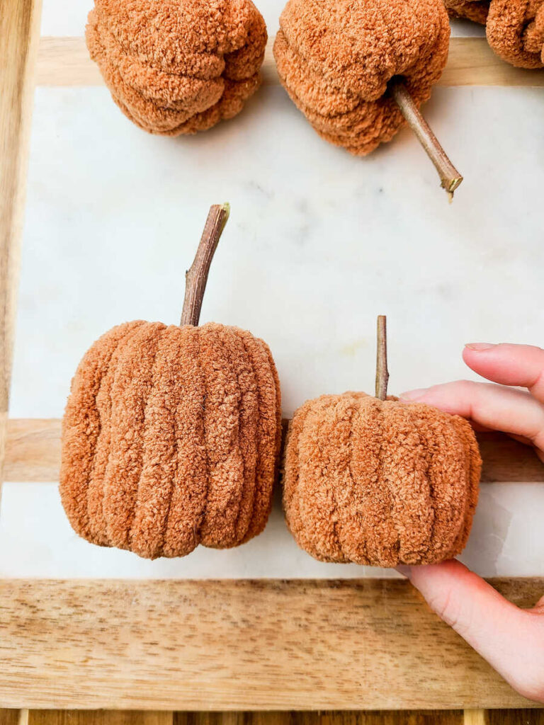 two plush pumpkins in a horizontal line next to each other on a marble background. 