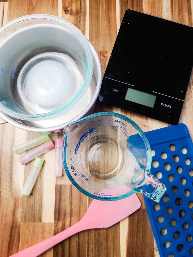 tools to make peppermint lip balm set out on wood counter top.