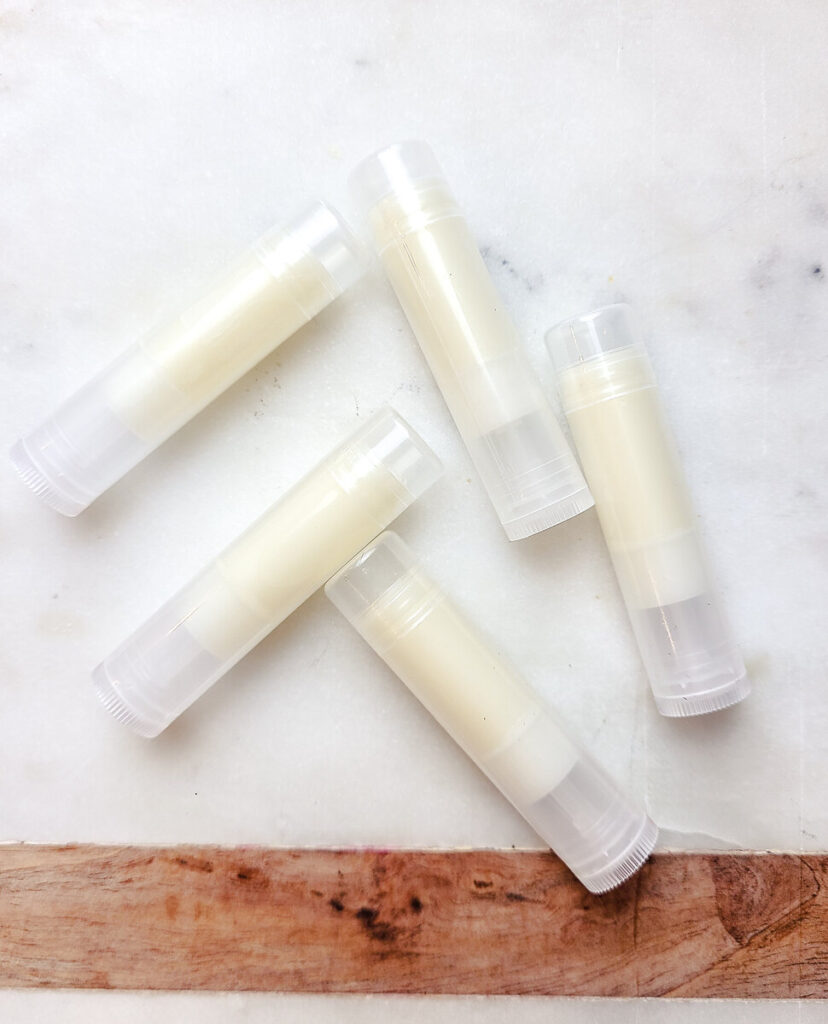 filled lip balm tubes laying flat on marble counter top. 