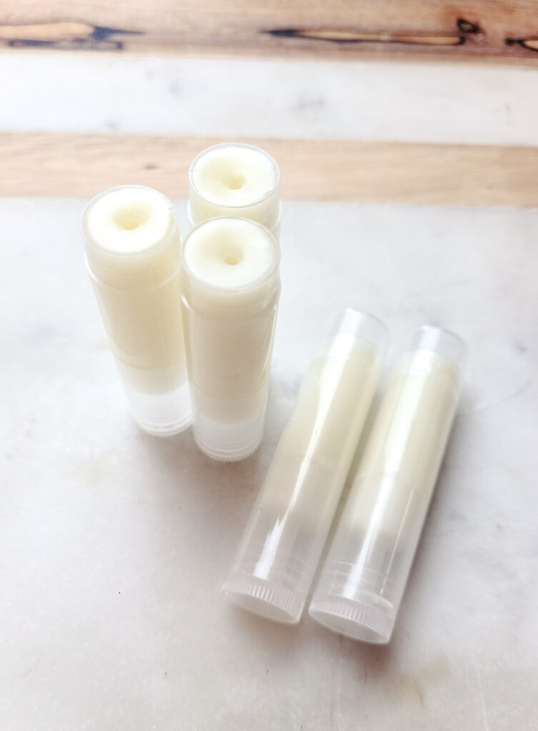 three white lip balms standing straight up, 2 lying down. All without caps. 