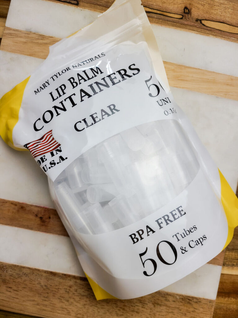 bag of 50 clear lip balm tubes from Mary Taylor Naturals laying on a cutting board. 