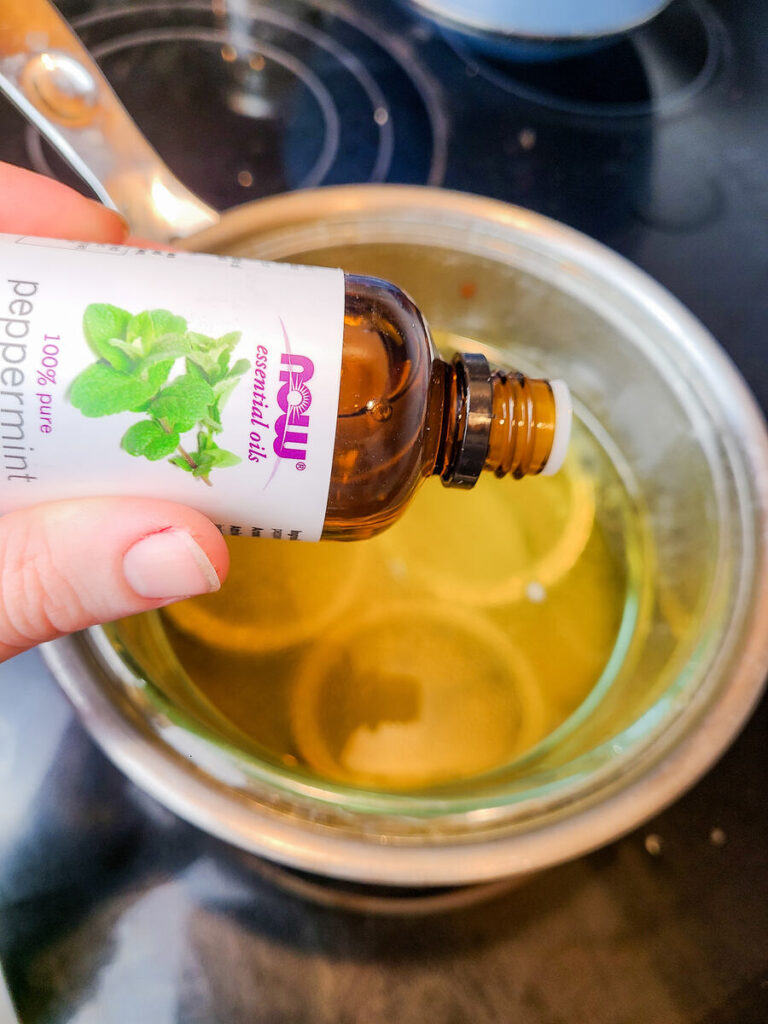 woman adding a few drops of NOW peppermint essential oil into lip balm mixture