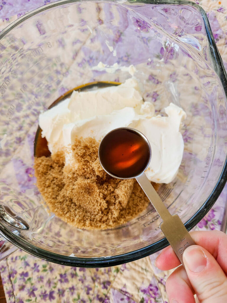 woman adding vanilla to cream cheese mixture 