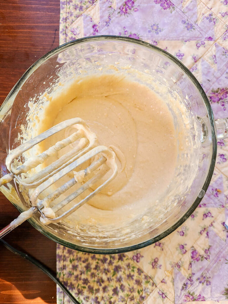 woman blending cream cheese ingredients with hand mixer until smooth