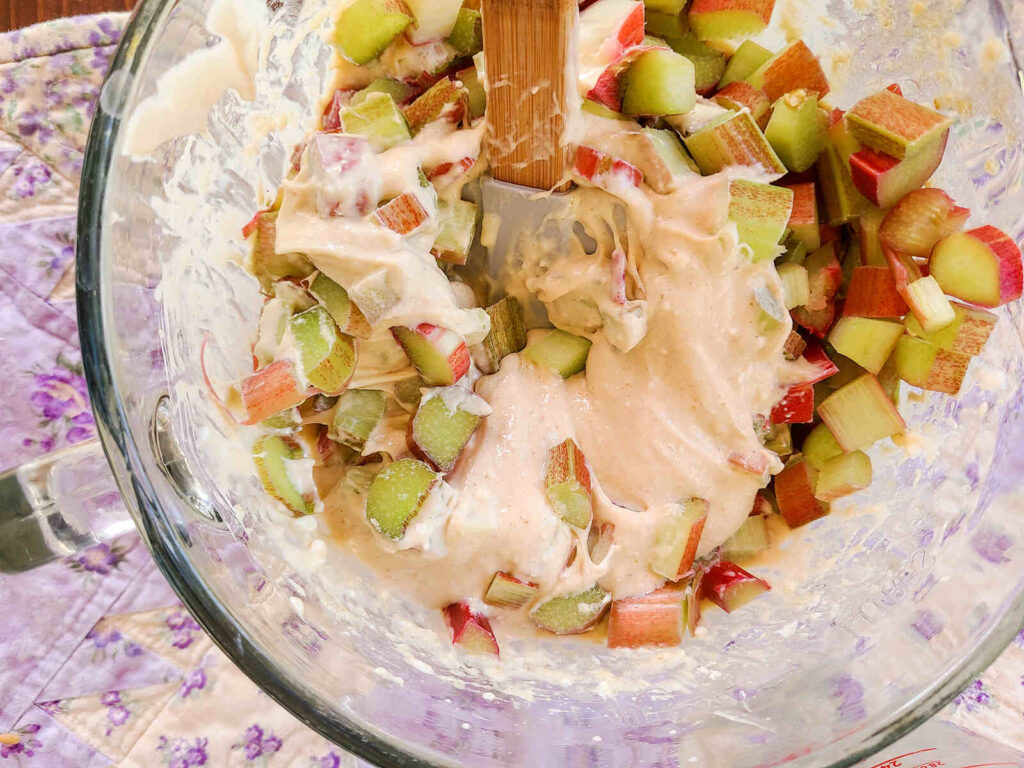 woman folding in chopped rhubarb to cream cheese mixture