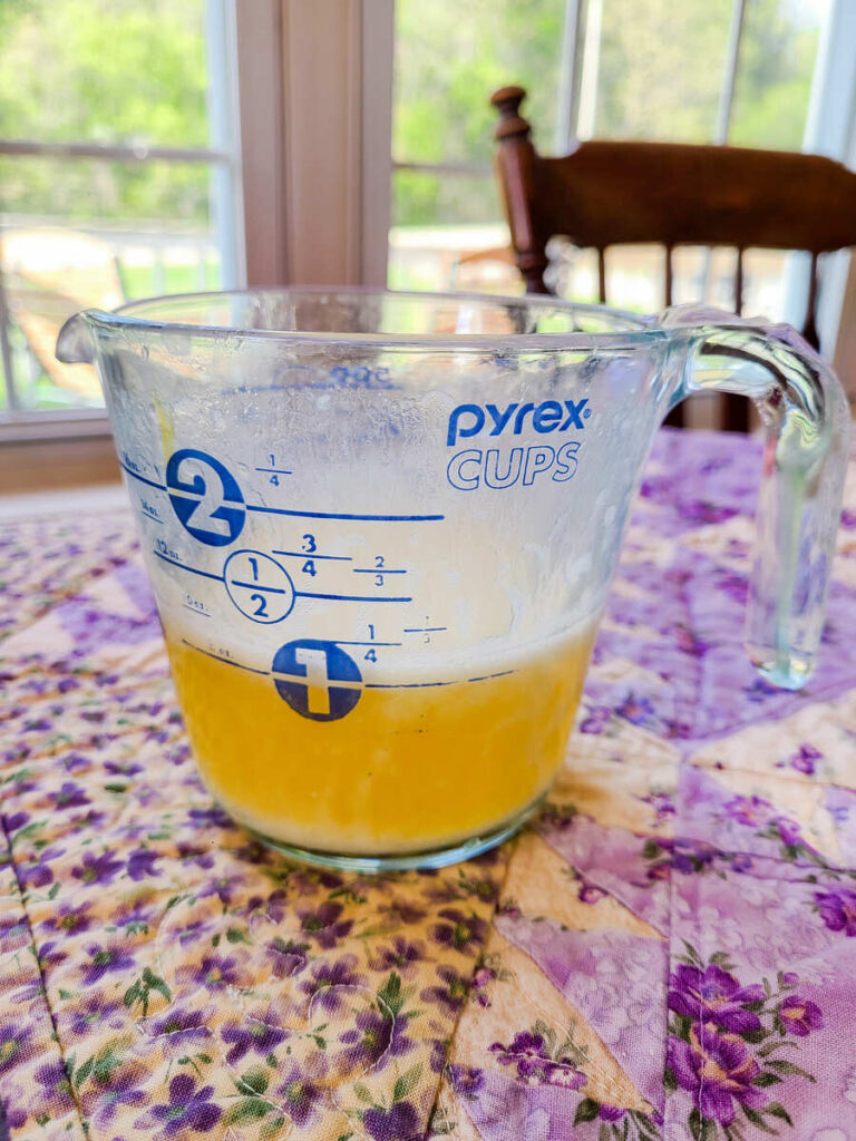 glass liquid measuring cup of melted butter on kitchen table 