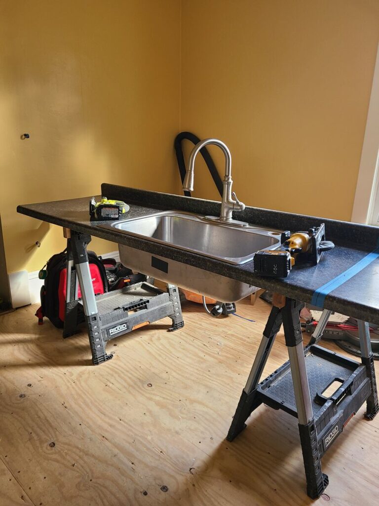 yellow room with kitchen counter and inset sink leaning on top of 2 saw horses. 