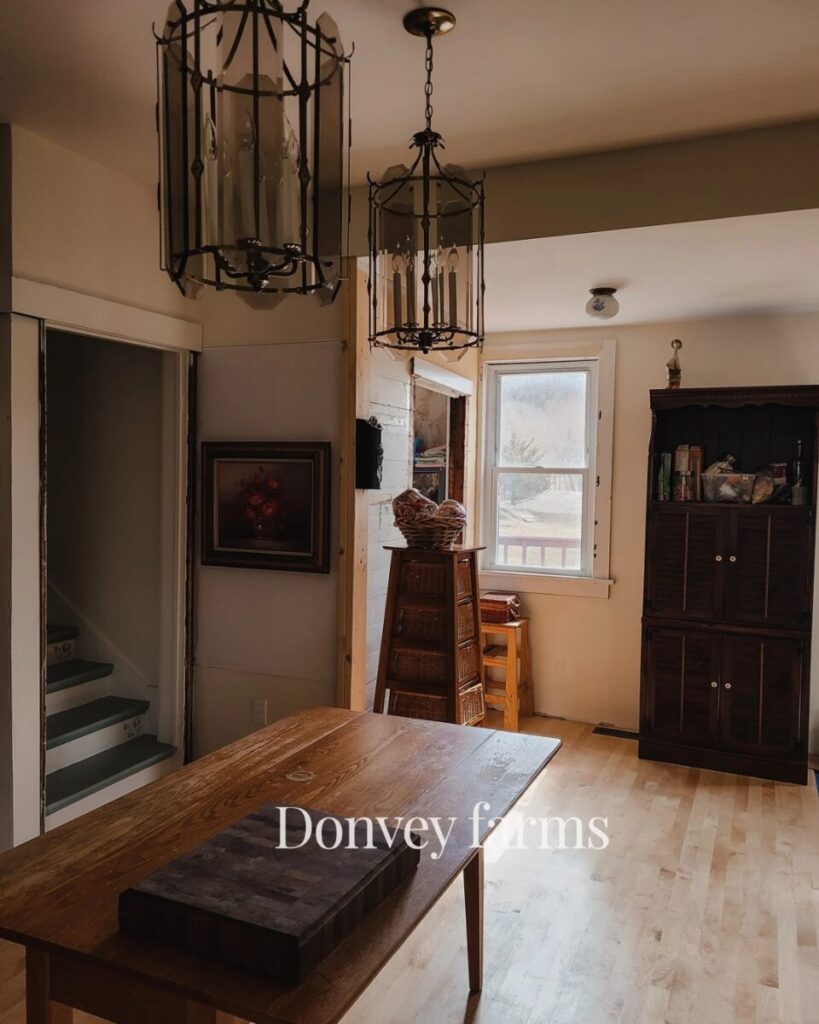 clean kitchen with a wood table in the center, a stacked whicker basket shelf and dark hutch at the back 