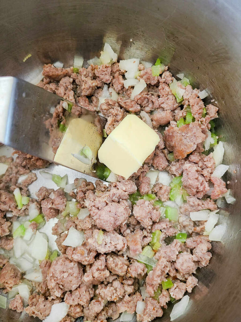 woman adding butter, chopped celery and onions into instant pot with ground pork to sauté