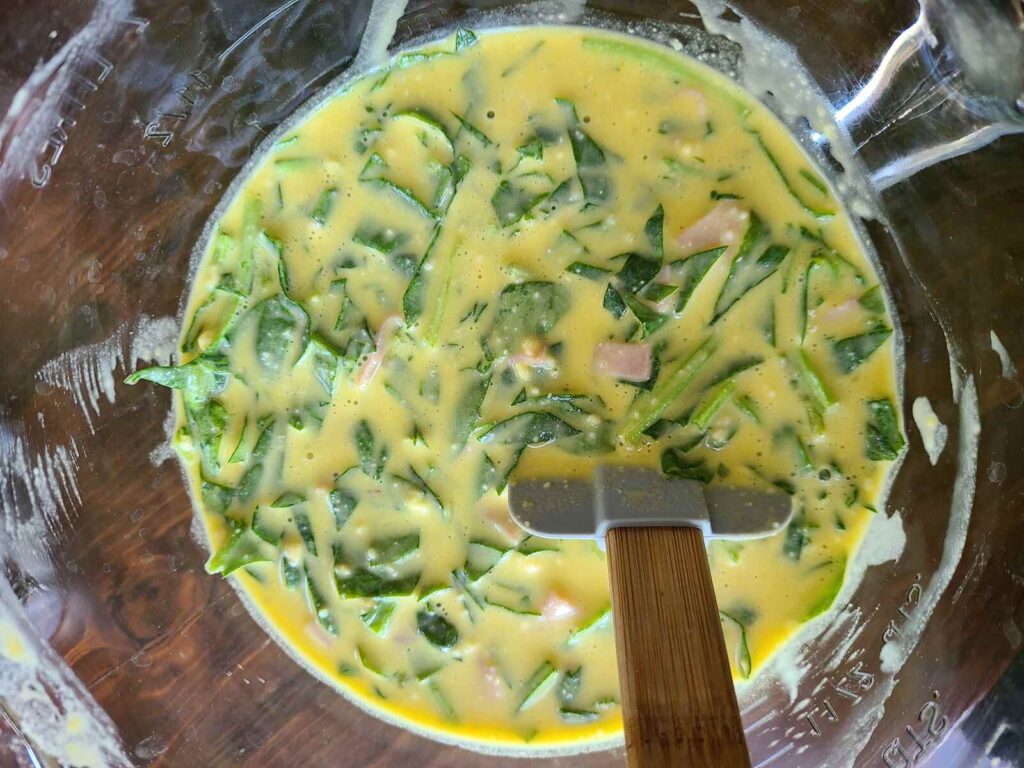woman stirring savory German pancake batter with spinach and ham 
