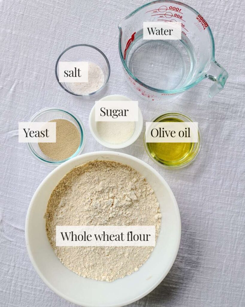 ingredients for whole wheat bread measured into separate containers and arranged on table. 