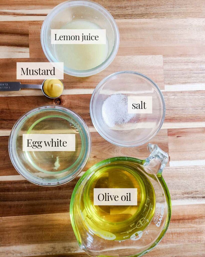 ingredients for egg white mayonnaise pre-measured into small glass bowls on counter top. 