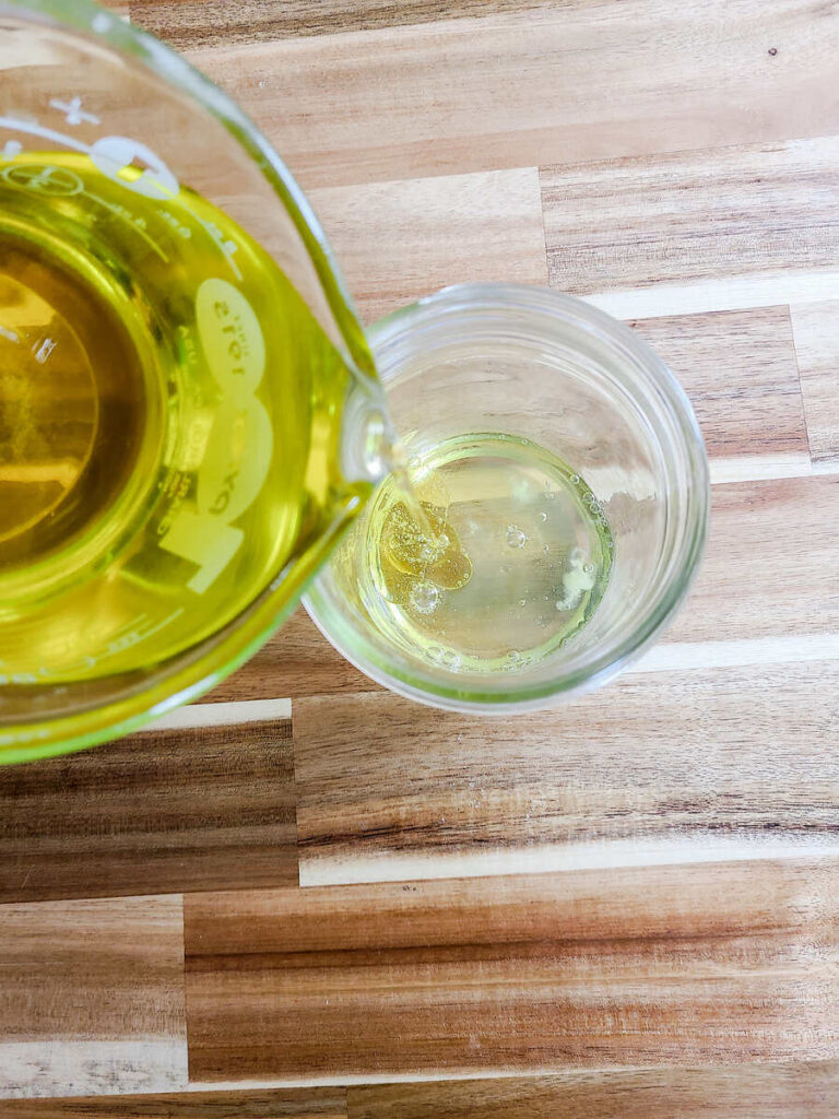 woman pouring oil into jar with egg whites 