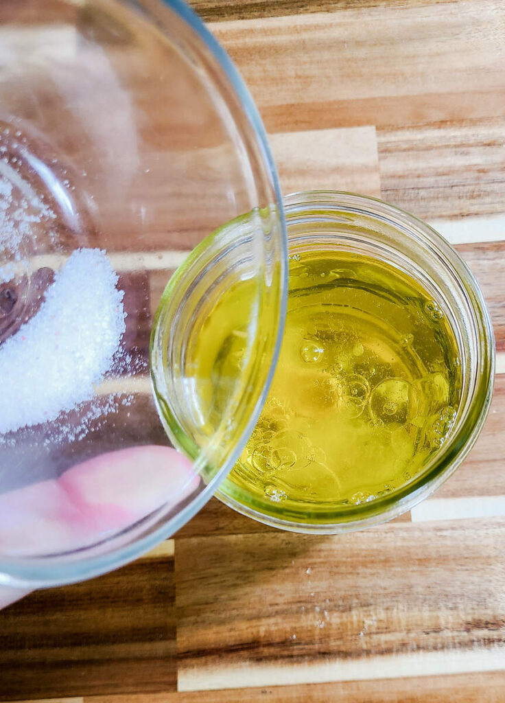 woman adding salt to oil mixture in jar 