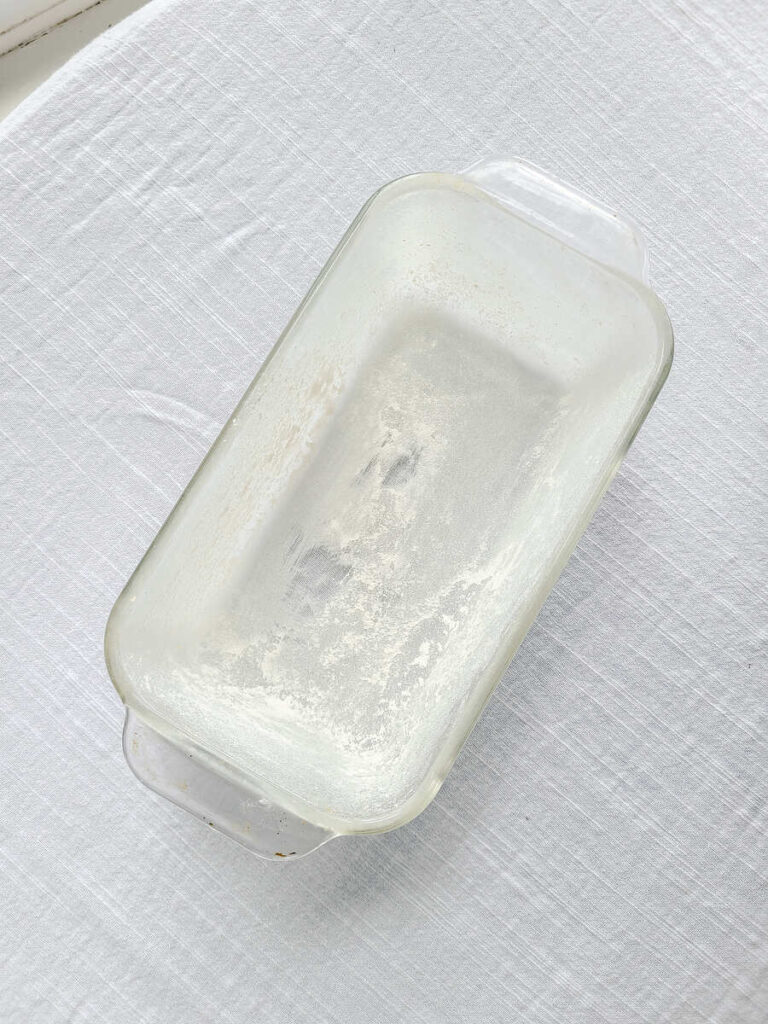 greased and floured glass 9" by 5" loaf pan on white table cloth 