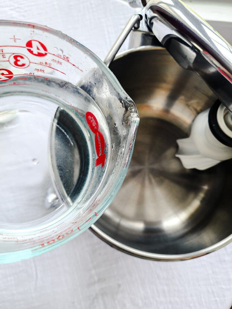 woman pouring water into standing mixer bowl 