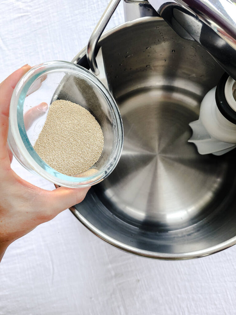 woman adding yeast to water in standing mixer bowl 