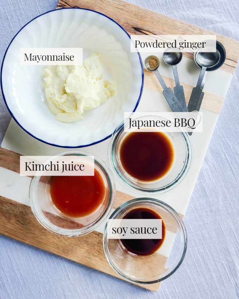 ingredients for kimchi mayo pre measured into containers and set out on marble cutting board. mayo, ginger, kimchi juice, Japanese BBQ and soy sauce