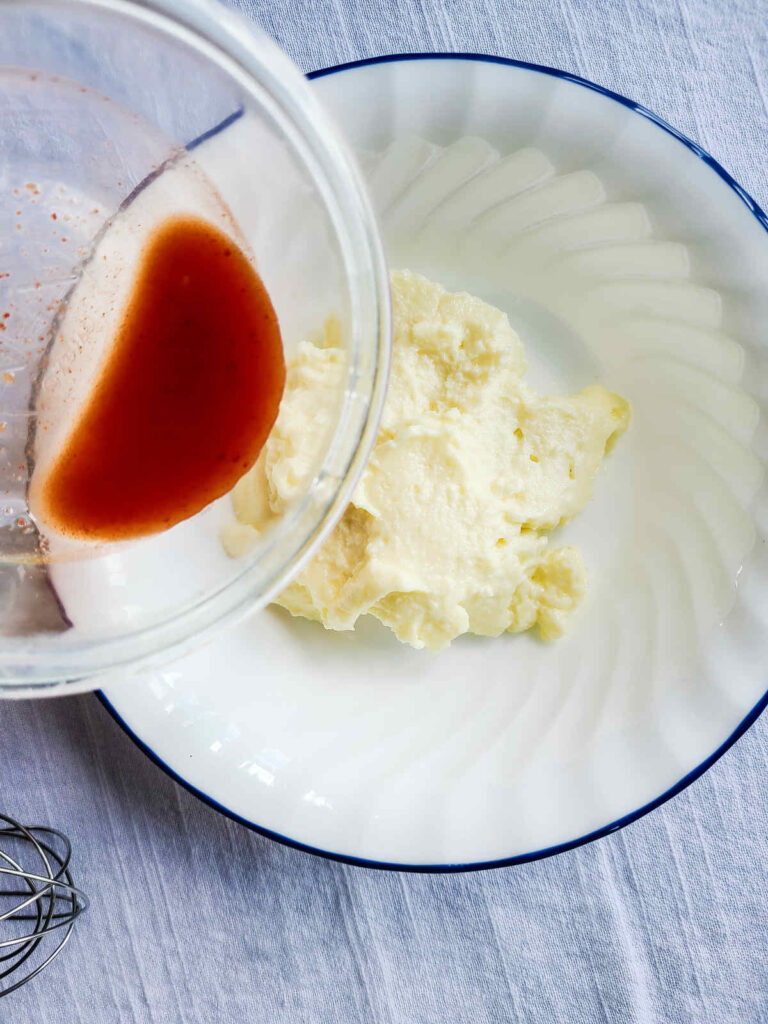 woman adding mayo and kimchi liquid to bowl